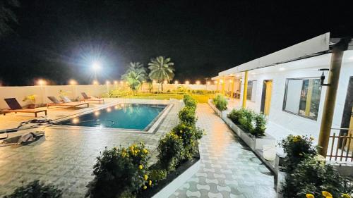a house with a swimming pool at night at Devka Farm House in Daman