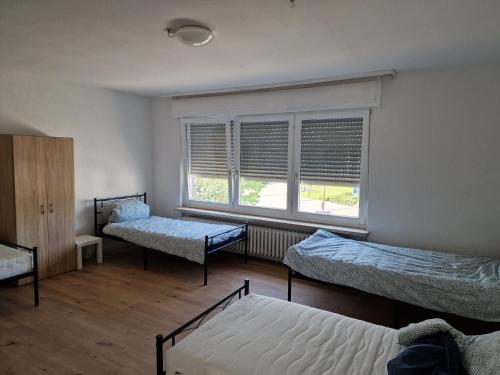 a room with three beds and a window at Monteurzimmer nahe Mannheim, Heidelberg, Karlsruhe, Bruchsal, Philippsburg, Speyer in Oberhausen-Rheinhausen