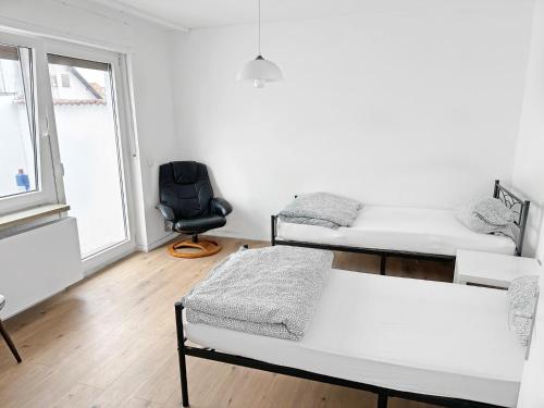 a white room with two beds and a chair at Monteurzimmer nahe Mannheim, Heidelberg, Karlsruhe, Bruchsal, Philippsburg, Speyer in Oberhausen-Rheinhausen
