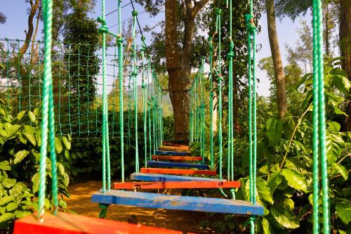 a rope bridge in a park with red and blue benches at The Grand Retreat - Chikmagalur in Chikmagalūr