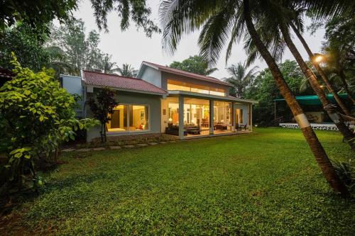 a house with large windows and a yard at Banyan Tree Pool Villa at Surya River Thane in Pālghar