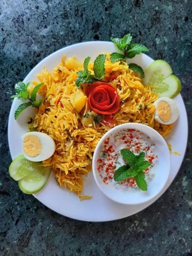 a plate of food with noodles and a bowl of sauce at Banyan Tree Pool Villa at Surya River Thane in Pālghar