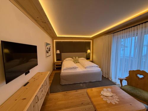 a bedroom with a large bed and a table at Alpenland - Das Feine Kleine in Lech am Arlberg