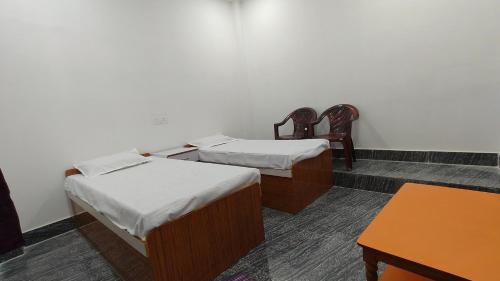 2 posti letto in una camera con 2 sedie e un tavolo di Hotel M P Anand Palace a Gaya