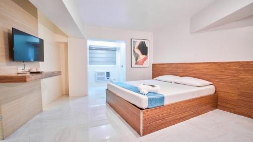 a bedroom with a bed and a flat screen tv at Circuit Hostel in Manila