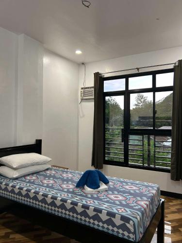 a bedroom with a bed and a large window at Seaslugs Travellers Inn in El Nido