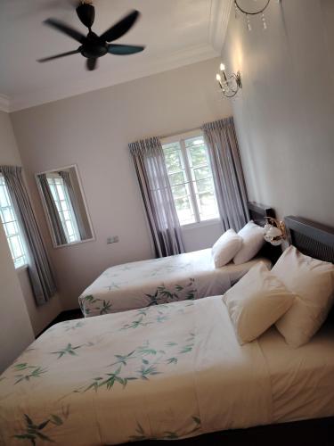 a bedroom with two beds and a ceiling fan at Cameron Greenhill Apartment in Cameron Highlands