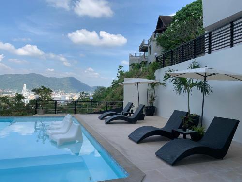 a swimming pool with chairs and umbrellas on a building at Patong Cliff Villa Phuket 12 bedroom in Patong Beach