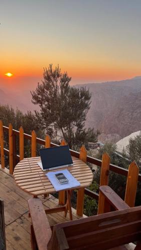 a laptop sitting on a wooden table on a deck with the sunset at Dana luxury huts in Dana
