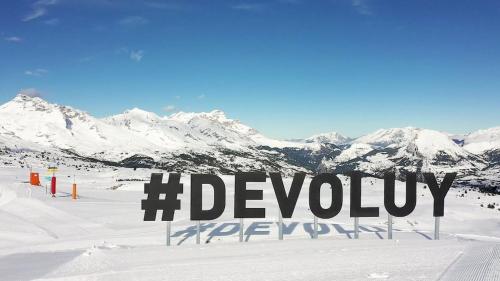 un panneau dans la neige avec des montagnes en arrière-plan dans l'établissement Appartement familial aux pieds des pistes, à Saint-Étienne-en-Dévoluy