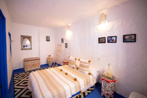 a bedroom with a bed with white walls at Dar YAMINA RASELMA in Chefchaouene