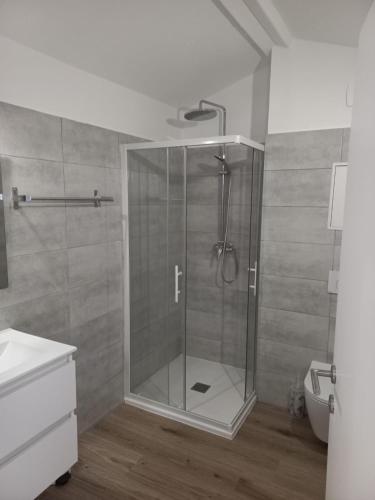 une douche avec une porte vitrée dans une salle de bain dans l'établissement Mini villa avec jardin Cala Rossa - Porto Vecchio, à Lecci