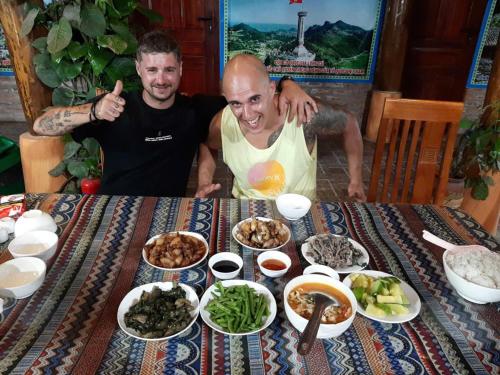 two men sitting at a table with plates of food at Ha Giang Eco Bungalow in Ha Giang
