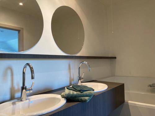 two sinks in a bathroom with a mirror and a tub at Hoeve Sterrewijk in Aalter