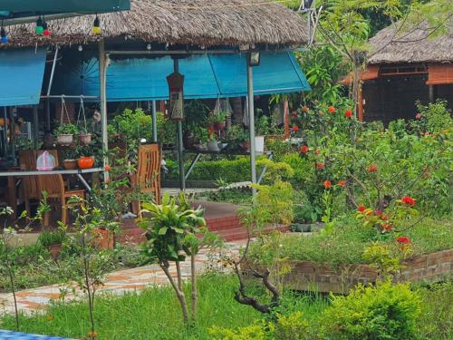a garden in front of a house with a thatch roof at Ha Giang Eco Bungalow in Ha Giang