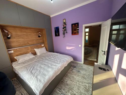 ein Schlafzimmer mit lila Wänden und einem großen Bett in der Unterkunft Registan view apartment in Samarkand