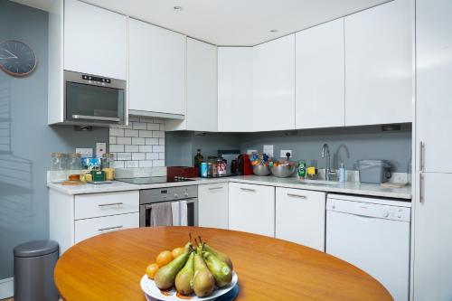 a kitchen with a wooden table with a bowl of fruit at London Bridge Escape - 2 Bed 2 Bath near landmarks in London