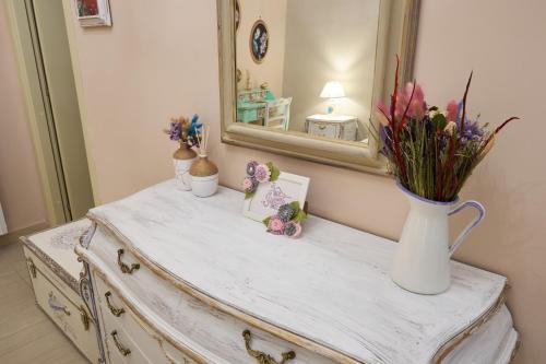 a dresser with a mirror and a vase of flowers on it at Luma ospitalità in Molfetta