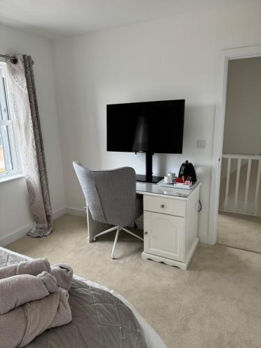 a bedroom with a desk with a television and a chair at Tobystar house in Plymouth