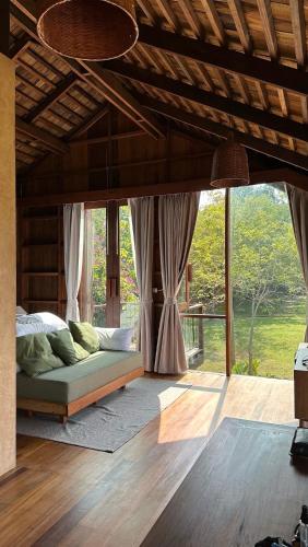 a bedroom with a bed and a large window at Nachan The Antique Courtyard in Chiang Khan
