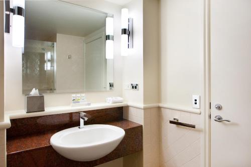 a bathroom with a white sink and a mirror at Mercure Gold Coast Resort in Gold Coast