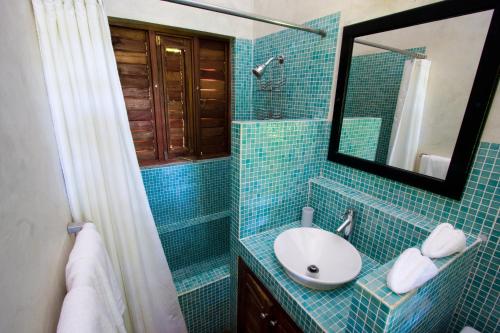a blue tiled bathroom with a sink and a mirror at Villas Sur Mer in Negril