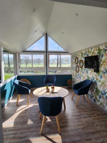 a living room with a table and chairs and windows at le cocon d'amour " le moulin Michel avec jaccuzi pour 12 personnes" in Pont-Bellanger