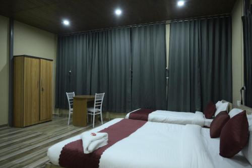 a bedroom with two beds and a table with chairs at Hotel Pohor Regency Near Kamakhya Gate Foot Bridge in Guwahati