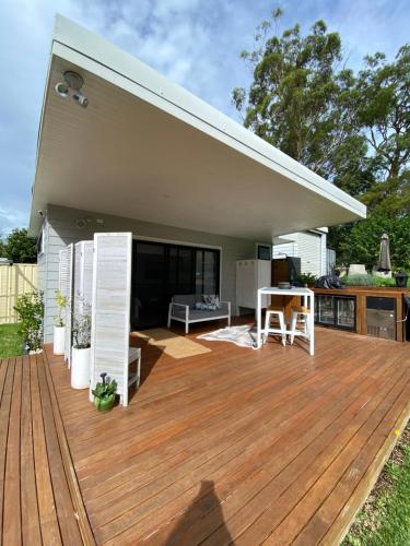 a wooden deck with a kitchen and a house at Golf Course & Beach Stay Self-Contained Guest House in Nelson Bay