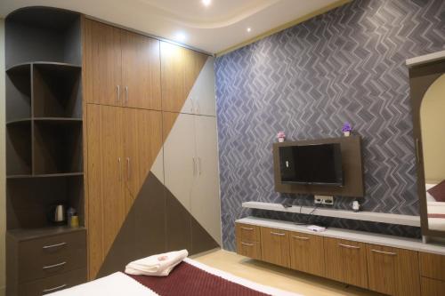 a bedroom with a tv on a wall at Hotel Pohor Regency Near Kamakhya Gate Foot Bridge in Guwahati