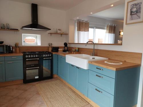 une cuisine avec des armoires bleues et un évier dans l'établissement Le Colibri, à Chambourg-sur-Indre