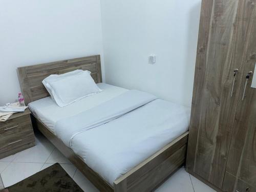 a small bed in a room with a wooden cabinet at Pleasant Stay Abu Dhabi in Abu Dhabi
