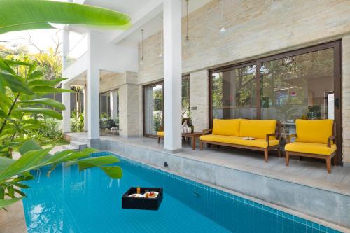 Una piscina con dos sillas amarillas al lado de una casa. en Melhor Stays Villa - L-M309 Luxury 3BHK villa with Private pool at Anjuna, en Arpora