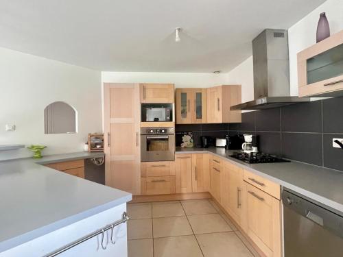 une cuisine avec des armoires en bois et des appareils en acier inoxydable dans l'établissement Maison avec Jardin Boussens Quartier Calme, à Boussens