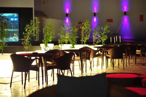 a group of tables and chairs in a room with purple lights at Golden Tulip Muscat in Muscat