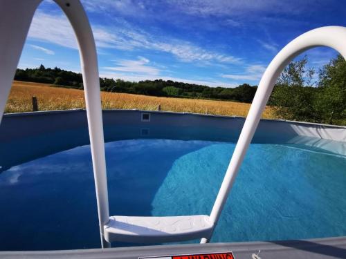une chaise dans une piscine avec vue sur un champ dans l'établissement Aux portes de Chambord, à Dhuizon