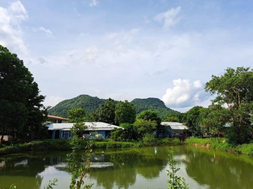 a river with houses and mountains in the background at Armthong Resort in Nakhon Nayok