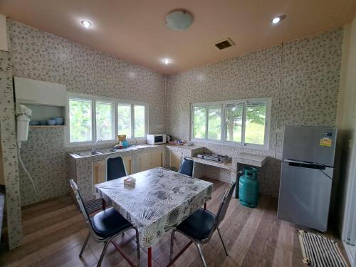 a kitchen with a table with chairs and a refrigerator at Armthong Resort in Nakhon Nayok