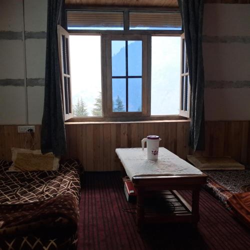 a room with a table and a bed and a window at Mountain's Melody Homestay in Sainj