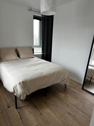 - un lit dans une chambre blanche avec un miroir dans l'établissement Maison 6 personnes, à Quincy-Voisins