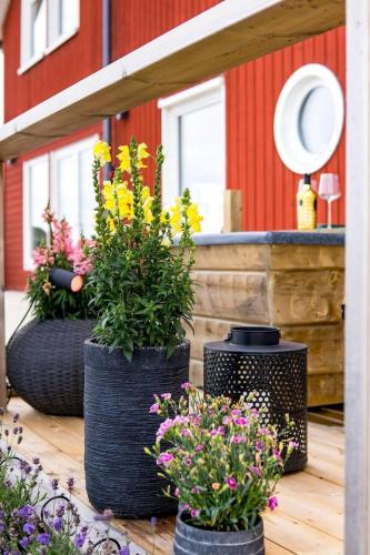three black vases with flowers on a patio at Comfortable Apartment with private dock in Gnarp