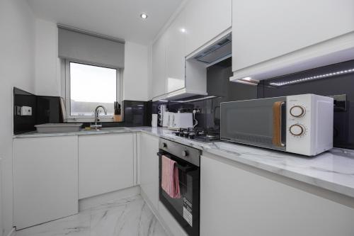 a kitchen with white counters and a microwave at Central Brighton Marina - Apartment - Sleeps 4 in Brighton & Hove