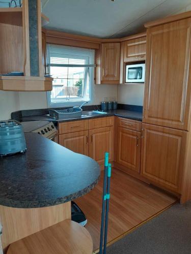 a kitchen with wooden cabinets and a black counter top at Dees caravan hire Ingoldmells Skegness in Ingoldmells