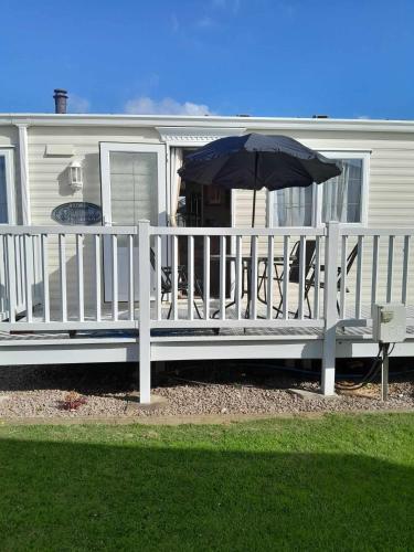 a white fence with an umbrella next to a house at Dees caravan hire Ingoldmells Skegness in Ingoldmells