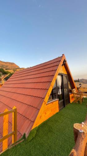 a cabin with a red roof on the grass at Dana luxury huts in Dana