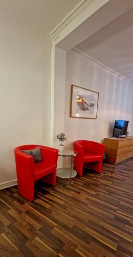 a living room with two red chairs and a table at City Apartments Triangeln in Malmö