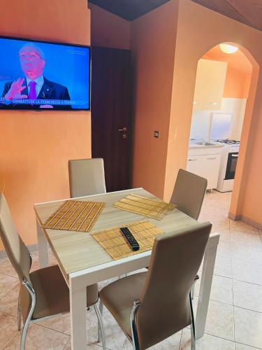a dining room table with chairs and a tv on the wall at La casa storica in Santu Lussurgiu