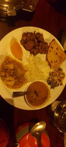 a white plate of food with meat and other foods at Heights Farm Stay - Coffee Estate Stay in Madikeri