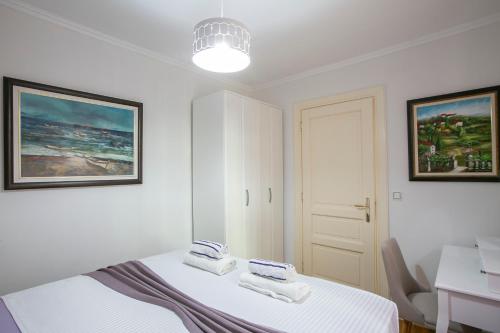 a white bedroom with a bed with towels on it at Montesan Luxury Apartments Sveti Stefan in Sveti Stefan
