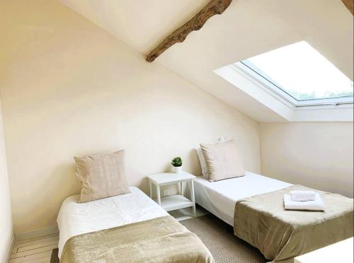 - 2 lits dans une chambre avec une lucarne dans l'établissement Le Cottage Brantôme, à Bourrou
